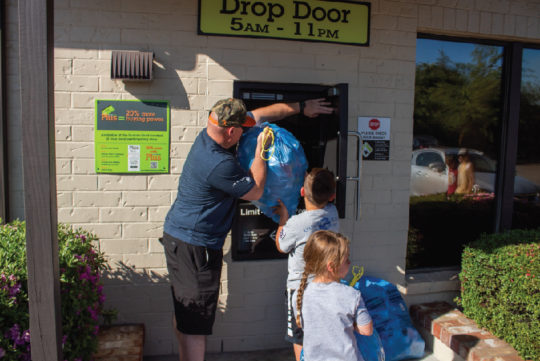 Man and Two Kids Depositing Blue Bags